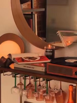 A sophisticated bar cart setup is presented, featuring glassware, books, and a lit candle, evoking a mood of relaxation and refined leisure.